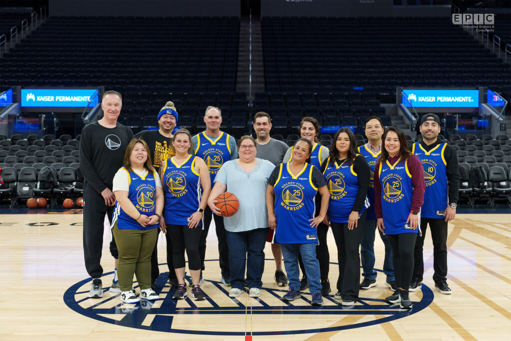 A group of people wearing Golden State Warriors jerseys posing on a basketball court.