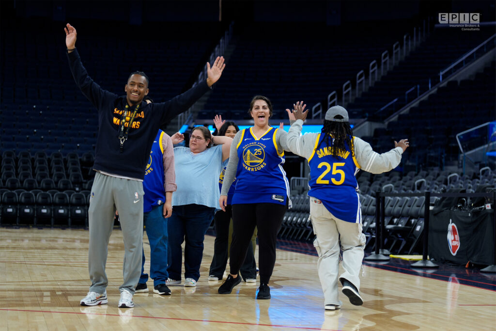 Individuals participating in a group activity on a basketball court, with one person wearing a Golden State Warriors jersey.